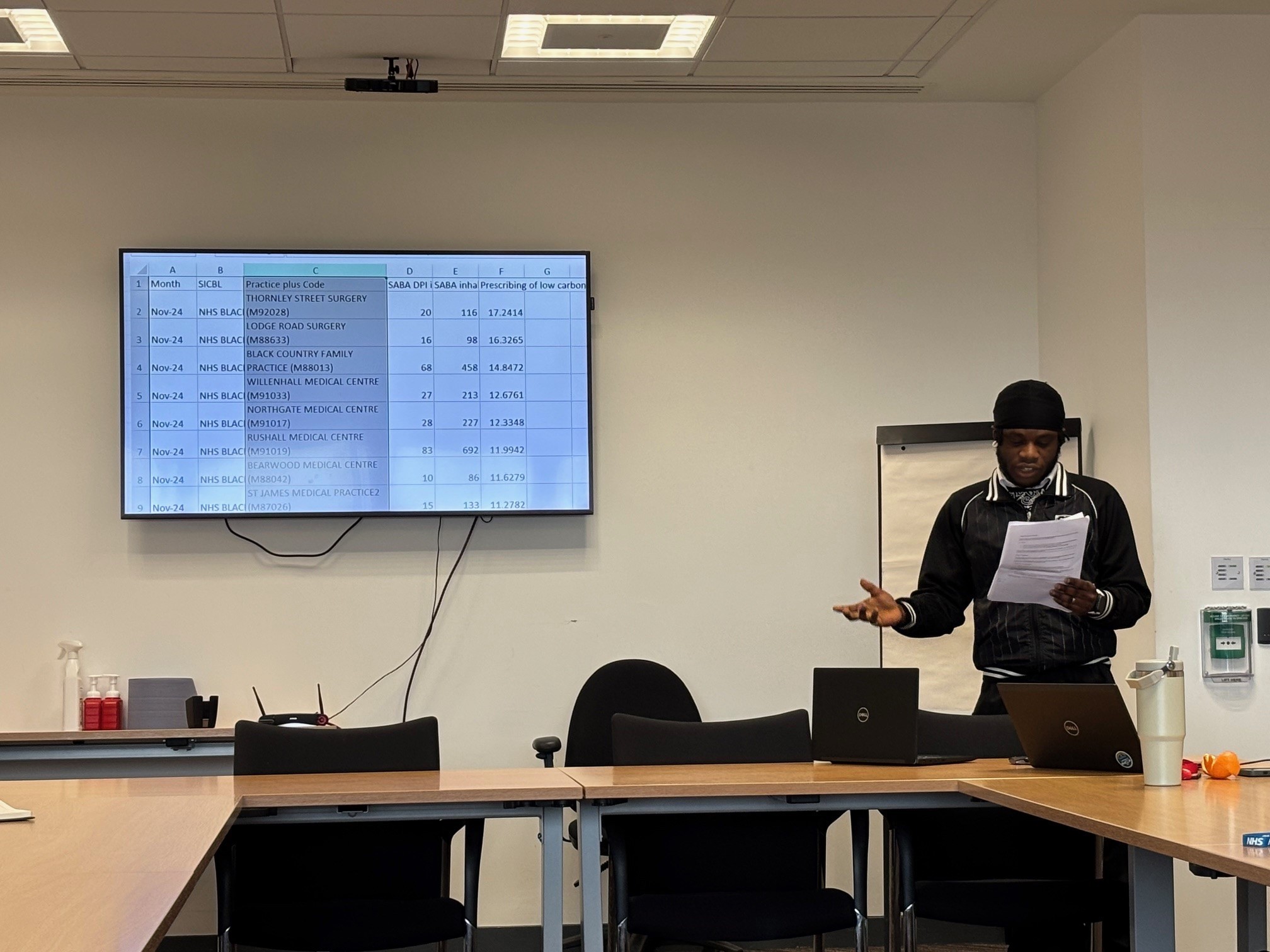 Young man presenting slides in front of large screen